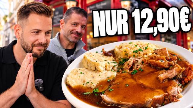 Zwei Männer vor einem Wirtshaus, vorne ein Teller mit Braten, Knödeln und Sauerkraut.